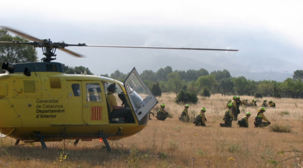 Un grup de Bombers desplegats davant de l'helicòpters durant unes tasques d'extinció. ACN Arxiu