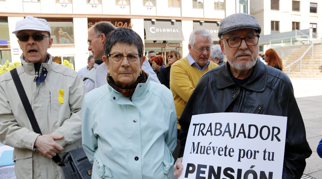 Dos jubilats, un dels quals sosté un cartell on es llegeix 'Trabajador, muévete por tu pensión', a la concentració de pensionistes de Lleida. Estela Busoms (ACN)