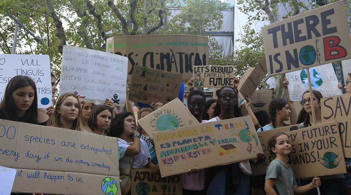 Diverses persones mostren pancartes alertant de l'emergència climàtica en el marc d'una manifestació a Barcelona de Fridays for Future. Laura Fíguls (ACN)