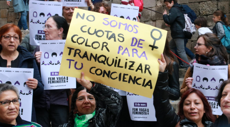Dues dones amb cartells reivindicatius en la presentació de la vaga feminista a la plaça del Rei de Barcelona. Aina Martí (ACN)